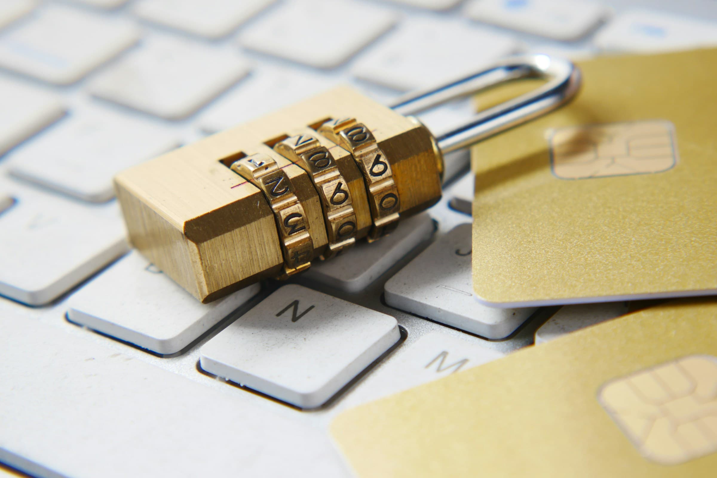 Un cadenas à combinaison posé sur un clavier d’ordinateur, à côté de cartes bancaires.