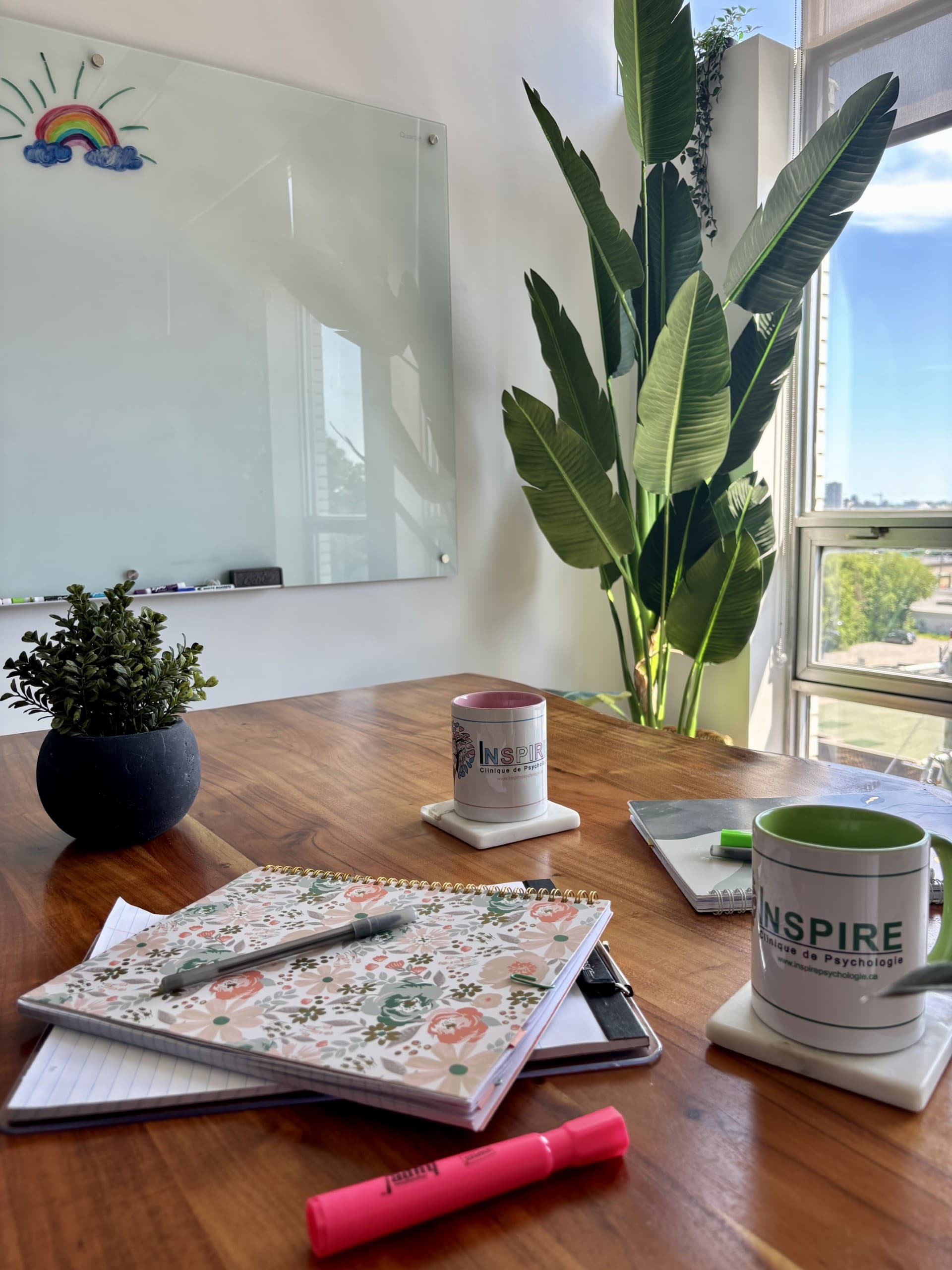Une table de réunion de la clinique, avec des cahiers de notes et des tasses Inspire.